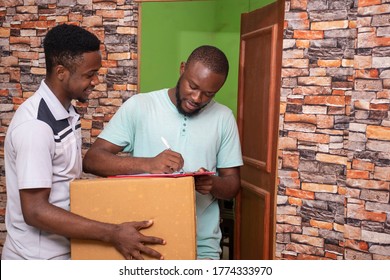 African Man Receives A Parcel From A Delivery Service Worker, Signs Off