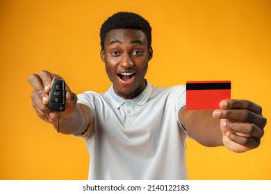 African Man Showing Car Key And Credit Card Over Yellow Background