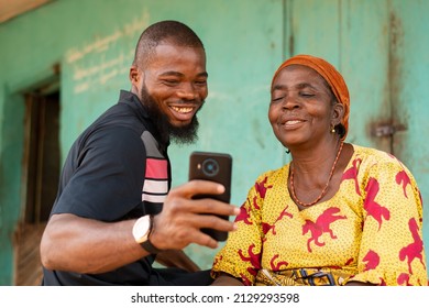 African Man Shows An Old African Woman Interesting Content On His Phone