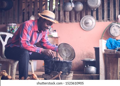 African man sitting to blow fire to cook food