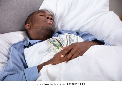 African Man Sleeping On Bed With Bundle Of Currency Notes