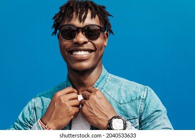 african man in sunglasses stands against a blue wall of a building in the city, handsome black man smiling