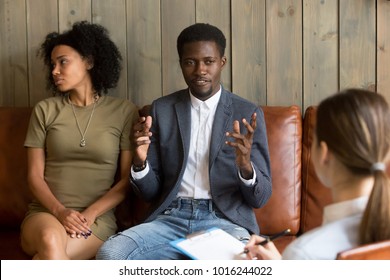 African Man Talking To Family Counselor, Frustrated Husband Sharing Marital Problems While Offended Wife Sitting Silent On Couch, Black Unhappy Couple Visiting Psychologist, Marriage Counseling