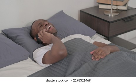 African Man Talking On Smartphone While Sleeping In Bed, Close Up