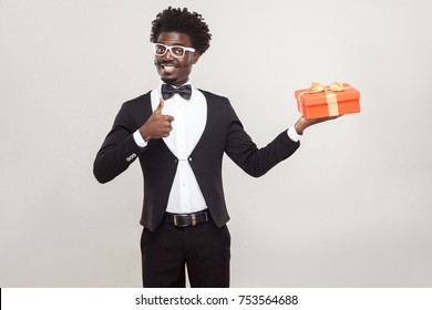 African Man Thumbs Up And Holding Gift Box. Studio Shot, Gray Background