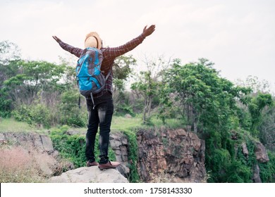 African man traveler standing on the top of the cliff and with backpack
