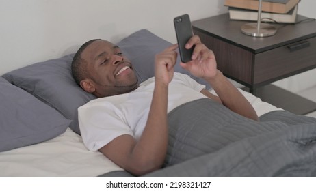 African Man Using Smartphone While Sleeping In Bed, Close Up