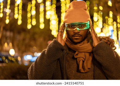 African man in warm clothes using smart glasses at night in the city during Christmas season