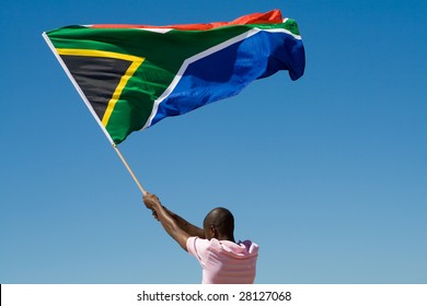 African Man Waving A South African Flag Against Blue Sky