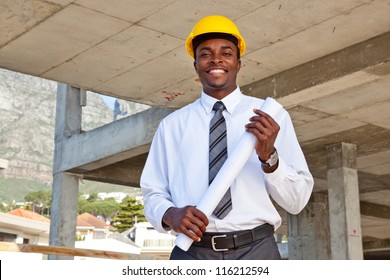 African Man Wearing A Hard Hat In A Construction Site Holding Building Plans