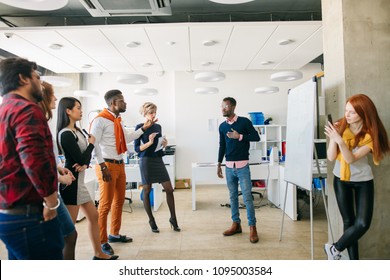 African Man In White T-shirt And Orange Trousers And His Team Asking Question In The Business Training In Modern Room