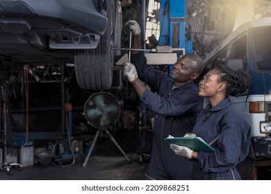 African man and woman car mechanics working in vehicle repair shop, black male mechanic wears overall clothes work in auto garage with black female mechanic standing beside during car maintenance job - Powered by Shutterstock