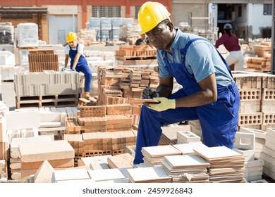 African man worker of a hardware store keeps records of ceramic paving slabs - Powered by Shutterstock