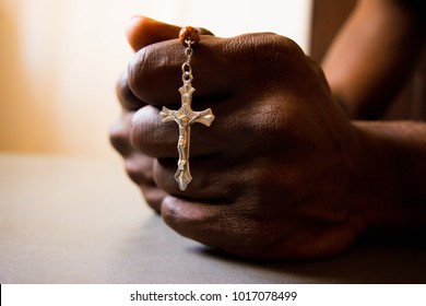 African man's hand holding Cross in prayer 