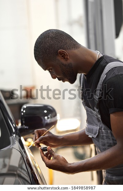 african man\'s hands use the detail brush to paint\
car or to clean and remove the dirt, car detailing and car wash\
painting concept
