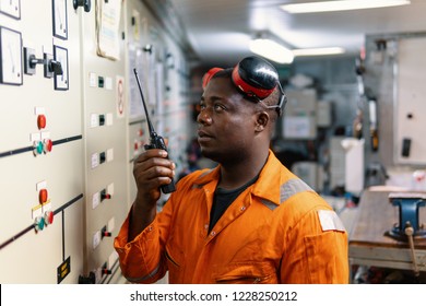 African Marine Engineer Officer In Engine Control Room ECR. He Speaks With VHF Or UHF Portable Radio. Ship Communication Routine