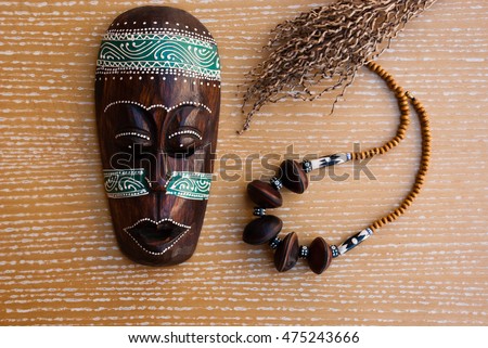 African mask with necklace and decorative branch. Tribal jewelry.