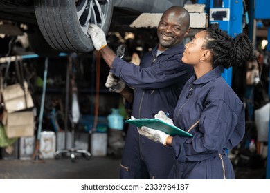 African mechanic workers fixing and checking a car or tire in automobile repair shop