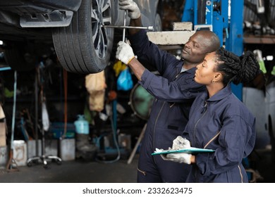 African mechanic workers using lug wrench for fixing a tire in automobile repair shop - Powered by Shutterstock