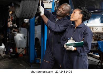 African mechanic workers using lug wrench for fixing a tire in automobile repair shop - Powered by Shutterstock