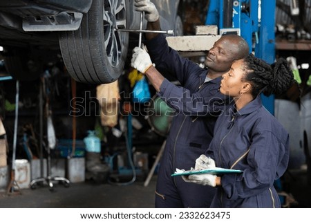 African mechanic workers using lug wrench for fixing a tire in automobile repair shop