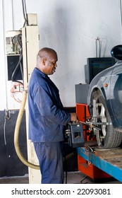 African Mechanic Working On A Vehicle Wheel Alignment