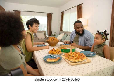 African Mixed Race Family Parents And Two Little Daughter Eating Fried Chicken And Pizza For Dinner Together. Father And Mother And Cute Child Girl Kid Enjoy Eating And Sharing A Meal Together At Home