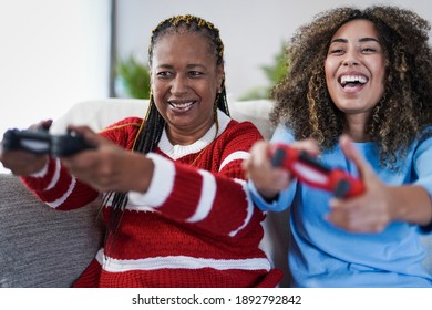 African mother and adult daughter have fun together at home playing video games