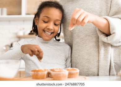 African mother and happy daughter decorating cupcakes together at home, cropped - Powered by Shutterstock