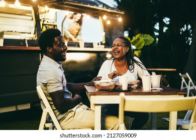 African mother and son eating food truck food outdoor - Focus on woman face - Powered by Shutterstock