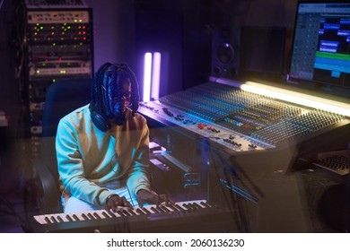 African Musical Producer Playing Electric Piano And Writing Music In The Recording Studio