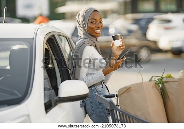 African muslim\
woman chraging car and use\
phone