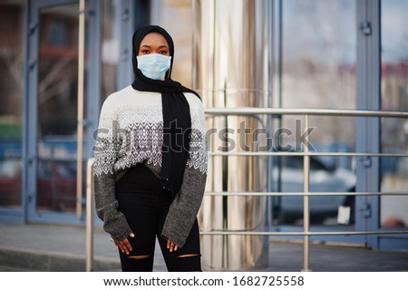 African muslim young volunteer woman wearing face mask and black hijab outdoors. Coronavirus quarantine and global pandemic.