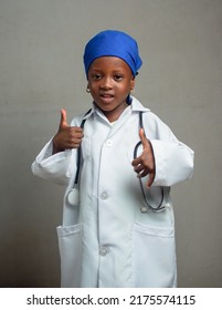 African Nigerian Girl Child With Blue Scarf And Stethoscope, Doing Thumb Up Gestures As She Represents Medical Experts Like Doctors, Nurses And Other Medical Practitioners