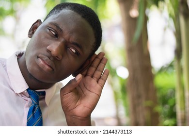 African Office Worker Man Listening Ear To Bad News Or Having Hearing Impair, Hard Of Hearing, Concept Image Of Auditory Ear Medication, Hearing Aid, Rumor, Fake News, Fact Check