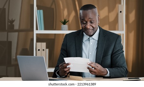 African Old Man Senior Mature Male In Office Opening Paper Envelope Reading Letter With Good News. Happy Elder Retired Businessman Received Investment Notification Banking Loan Approval Salary Bonus