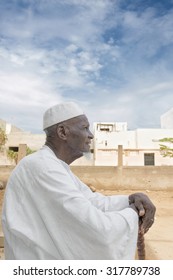 African old man sitting in front of his house, eighty years old