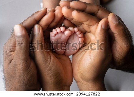 African parents holding the feet on a new born baby