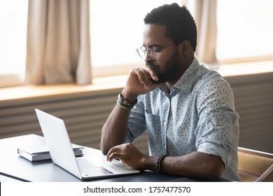 African pensive businessman sit at workplace desk in front of laptop thinking over received e-mail, business problem solution, make decision feels doubtful concerned uncertain search answer concept - Shutterstock ID 1757477570