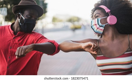 African people wearing face masks while bumping their elbows instead of greetings with hugs - Focus on woman's eye - Shutterstock ID 1823075471