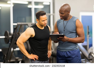 african personal trainer helping man to fill the membership form of health club