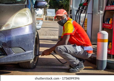 African Petrol Attendant Checking Tire Presure At A Gas Station In Botswana