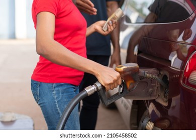 African Petrol Station Attendant Filling Up A Car, Holding Money