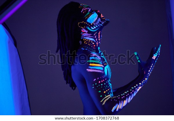 african prayer with UV body art glowing in darkness, colorful ethnic prints on naked skin. abstract fantastic futuristic paints, fluorescent make-up. man pray for the best