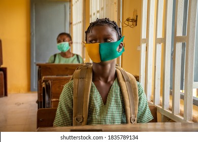 African Primary School Pupil's Sitting In Class, Wearing Face Masks, And Observing Physical Distancing, Sitting Far From Each Other