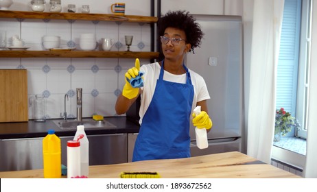 African Professional Janitor Cleaning Apartment In Apron And Rubber Gloves. Young Black Cleaner In Uniform Doing Housework In Modern House. Cleaning Service Concept