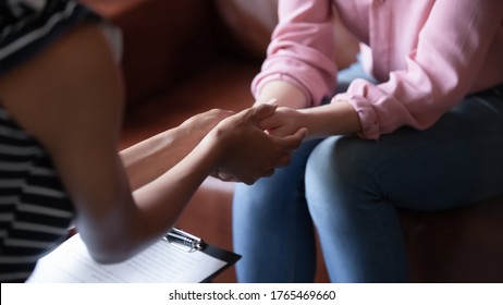 African psychologist hold hands of girl patient, close up. Teenage overcome break up, unrequited love. Abortion decision. Psychological therapy, survive personal crisis, individual counselling concept