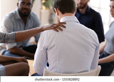 African Psychologist Put Hand On Shoulder Of Addicted Man Close Up Rear View Supporting Him, Diverse People Gathered At Rehab Group, Psychological Assistance Drugs Alcohol Addiction Treatment Concept