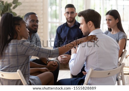 African psychologist supporting male rehab session participant put hand on newcomer shoulder talks encouraging words, medical detox center, psychological help activity struggle with addictions concept