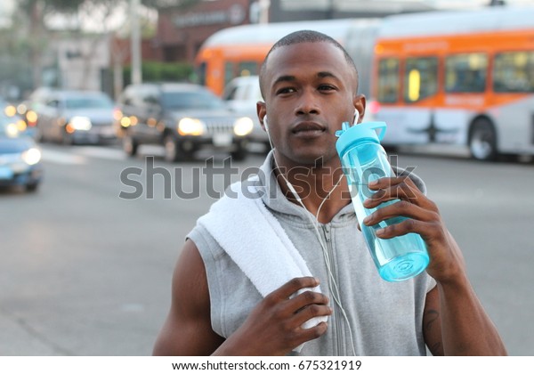 African runner drinking a\
sports drink 